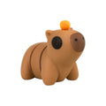 Beweegbare Tiny capybara lichtbruin met oranje sinaasappel op neus 5x2,5x4 cm schuin van voren op groene achtergrond